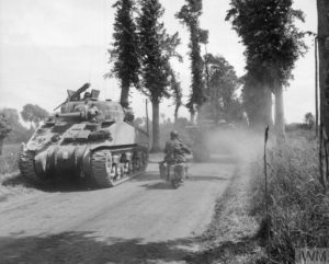 13 juin 1944 : forte activité de véhicules alliés sur une route de Normandie. Les chars M4 Sherman appartiennent au Royal Marines Armoured Support Group. Photo : IWM B 5456