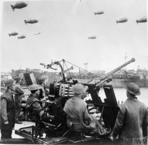 June 1, 1944: In a port in the south of England, British soldiers search the skies for enemy aircraft with their 40 mm Bofors anti-aircraft gun. In the background, LST (Landing Ship Tank) ships embark on boarding operations in preparation for Operation Overlord. Photo: IWM B 5152