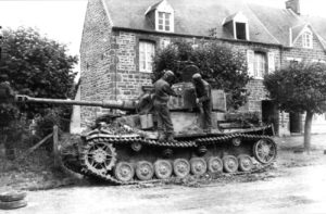 Deux « tankistes » américains inspectent un char allemand SdKfz 161 Panzerkampfwagen IV, numéroté 831 et neutralisé dans Saint-Denis-le-Gast par les hommes du 41st Infantry Regiment le 29 juillet 1944. L’un des soldats montre le point d’entrée de l’obus ayant pénétré la tourelle, à l’emplacement du chiffre « 1 ». Photo : US National Archives